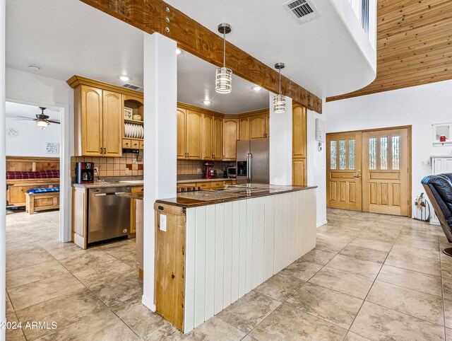 kitchen with appliances with stainless steel finishes, backsplash, a high ceiling, ceiling fan, and decorative light fixtures