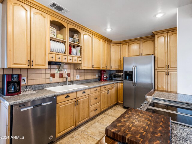 kitchen with decorative backsplash, stainless steel appliances, light tile patterned floors, and sink