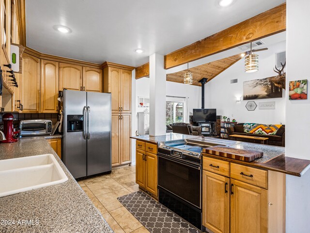 kitchen featuring pendant lighting, sink, black range oven, vaulted ceiling with beams, and stainless steel fridge