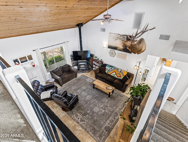 carpeted living room with wood ceiling, ceiling fan, a wood stove, and high vaulted ceiling