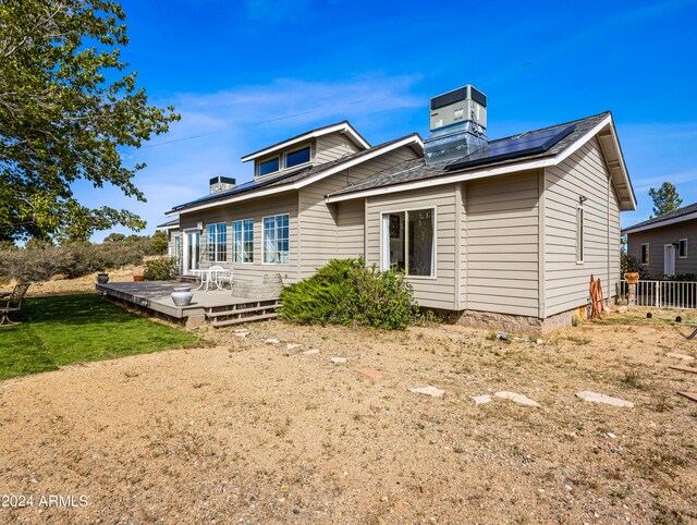 rear view of property featuring a deck and a yard