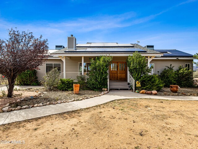 view of front facade featuring solar panels and covered porch