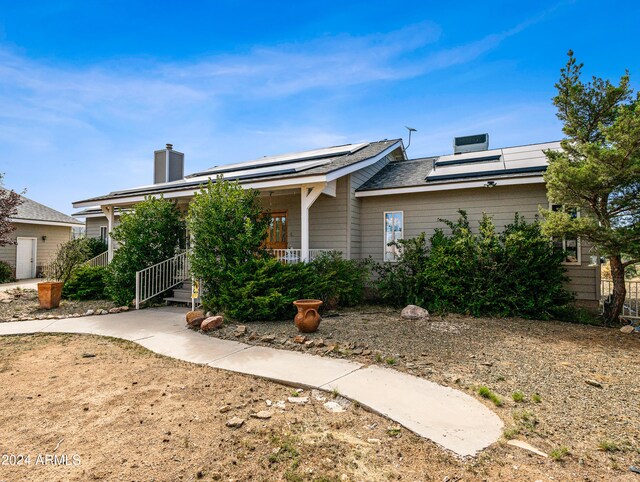 view of front of property featuring solar panels and a porch