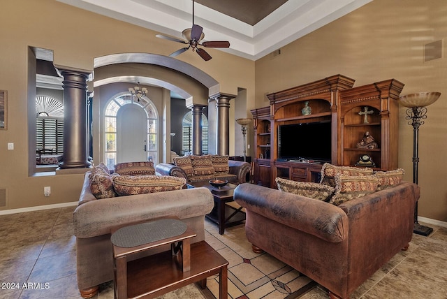 living room featuring decorative columns, light tile patterned floors, and ceiling fan with notable chandelier