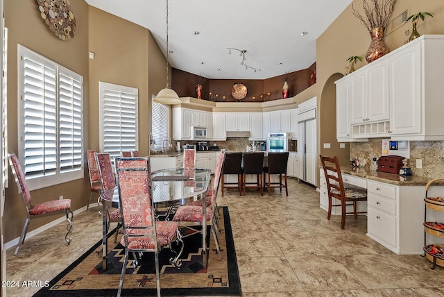 dining area with sink and a towering ceiling