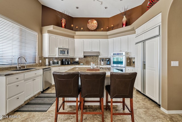 kitchen featuring appliances with stainless steel finishes, a center island, a high ceiling, and sink