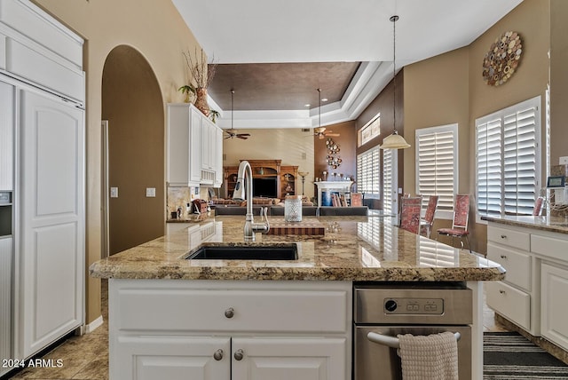 kitchen with ceiling fan, sink, decorative light fixtures, and a center island with sink