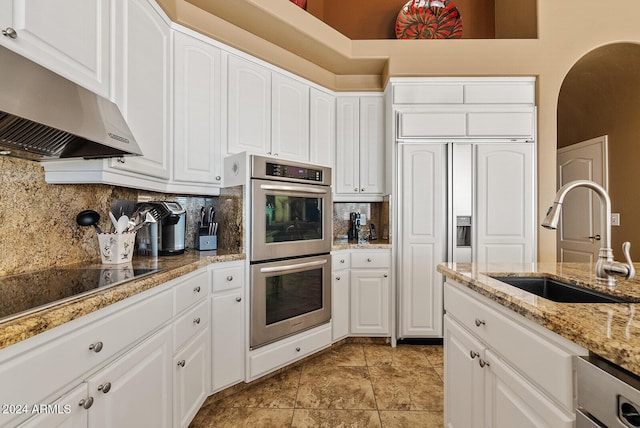 kitchen featuring double oven, white cabinetry, sink, and exhaust hood