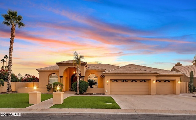 mediterranean / spanish-style home with a yard and a garage