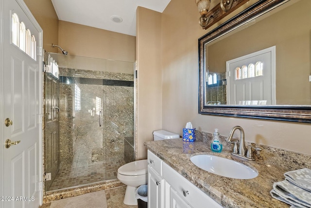 bathroom featuring tile patterned floors, vanity, a shower with shower door, and toilet