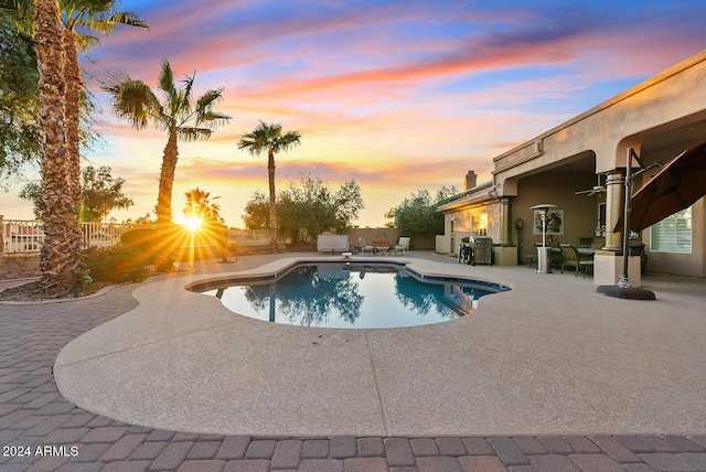 pool at dusk featuring a patio