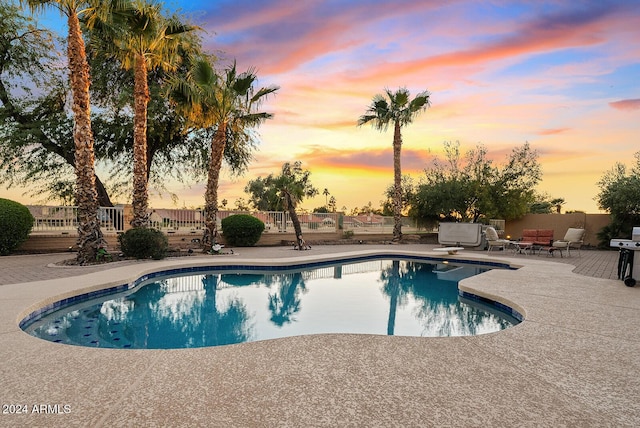 pool at dusk featuring a patio