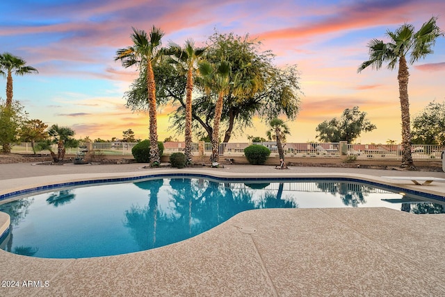 pool at dusk featuring a diving board and a patio