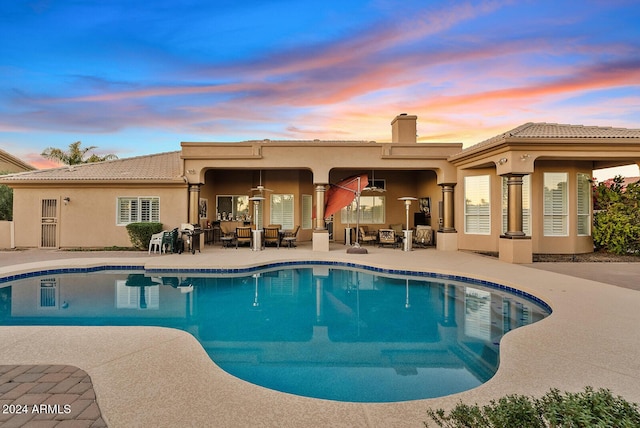 pool at dusk with a patio area