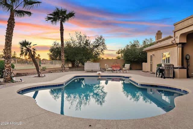 pool at dusk featuring a patio area and a grill