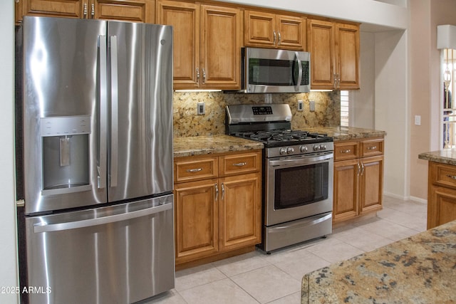 kitchen featuring tasteful backsplash, light tile patterned flooring, light stone countertops, and appliances with stainless steel finishes