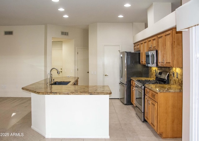 kitchen with sink, light stone counters, kitchen peninsula, stainless steel appliances, and decorative backsplash