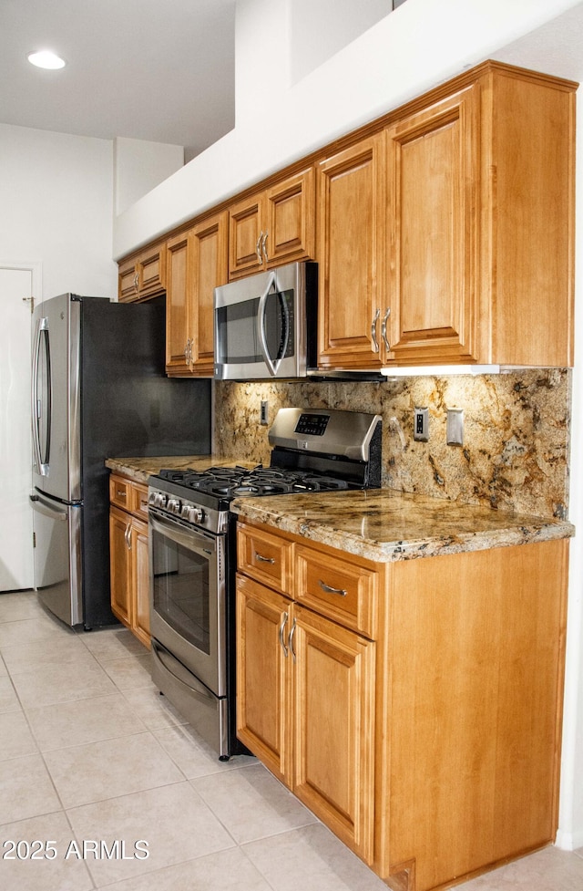 kitchen featuring tasteful backsplash, light stone countertops, light tile patterned floors, and stainless steel appliances