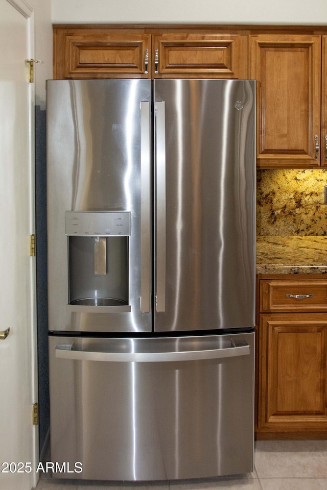 details with stainless steel fridge with ice dispenser and light stone countertops