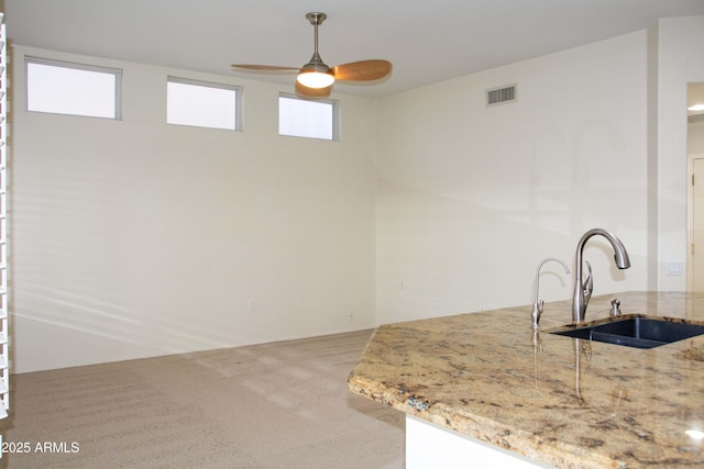 kitchen with sink, ceiling fan, light stone counters, carpet floors, and decorative light fixtures