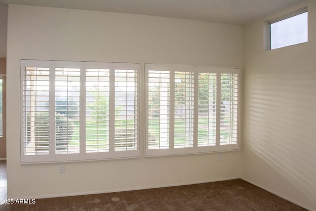 unfurnished room with dark carpet and plenty of natural light