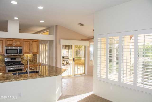 kitchen with light stone counters, sink, backsplash, and appliances with stainless steel finishes