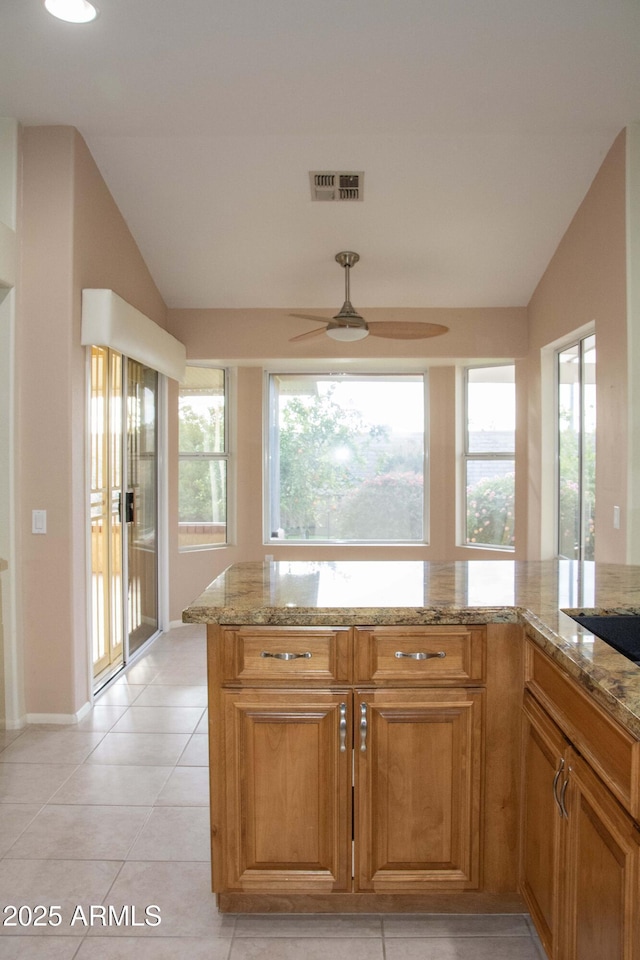 kitchen featuring lofted ceiling, light stone countertops, ceiling fan, and light tile patterned flooring