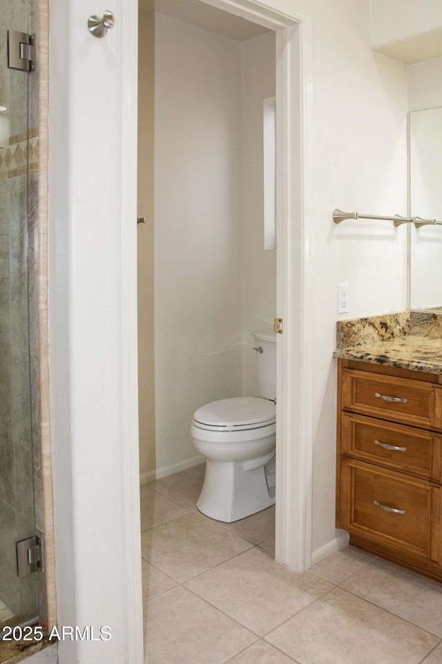 bathroom with tile patterned flooring, vanity, toilet, and walk in shower