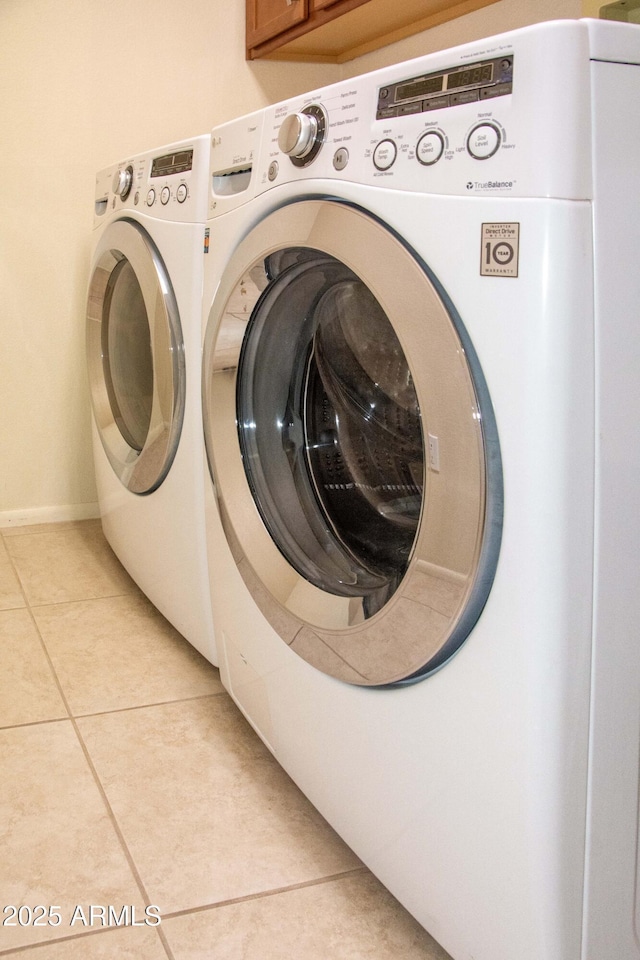 washroom with cabinets, washer and clothes dryer, and light tile patterned floors