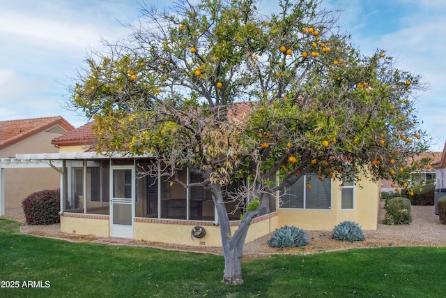 rear view of house with a yard and a sunroom