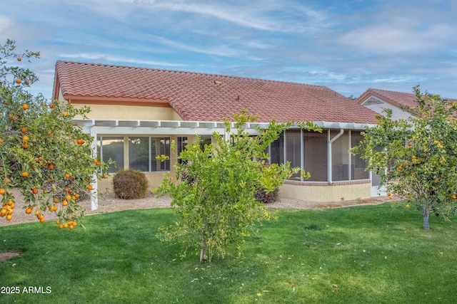 back of property with a yard and a sunroom