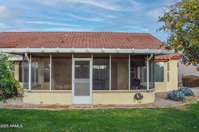 rear view of house featuring a sunroom and a lawn