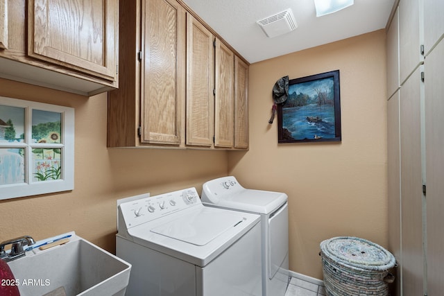 laundry area with cabinet space, visible vents, separate washer and dryer, and a sink