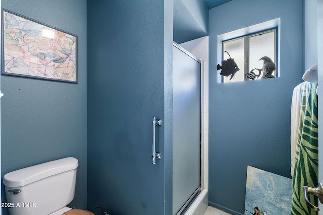 bathroom with a textured wall, a shower with shower door, and toilet