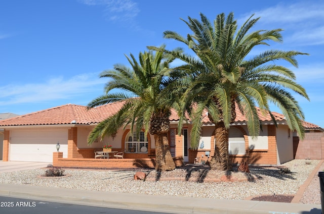 view of front of property featuring concrete driveway, a tile roof, and an attached garage