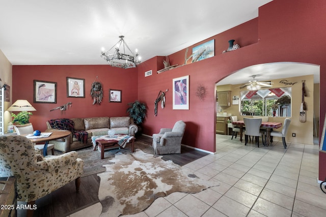 living room with light tile patterned floors, visible vents, arched walkways, lofted ceiling, and ceiling fan with notable chandelier