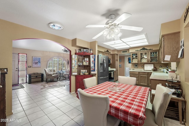 dining area with light tile patterned floors, ceiling fan, visible vents, and arched walkways