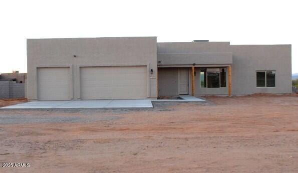 pueblo-style house featuring concrete driveway, an attached garage, and stucco siding