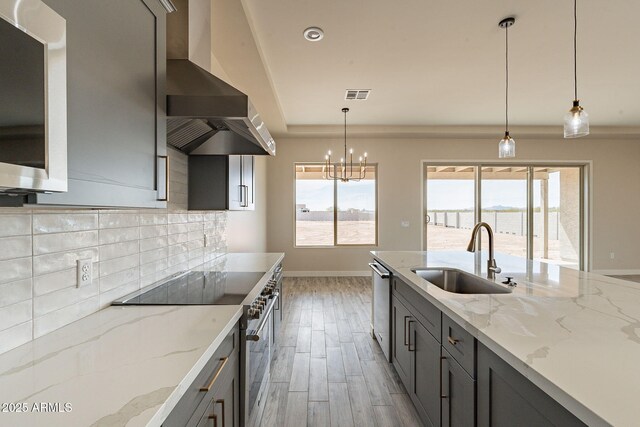 kitchen featuring plenty of natural light, stainless steel appliances, visible vents, a sink, and wall chimney exhaust hood