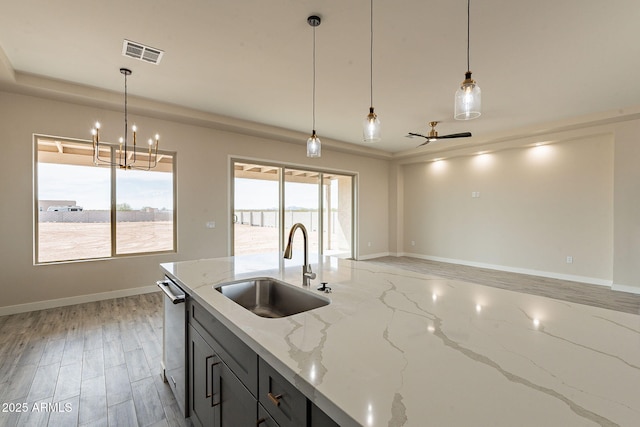 kitchen with dishwasher, visible vents, a sink, baseboards, and pendant lighting