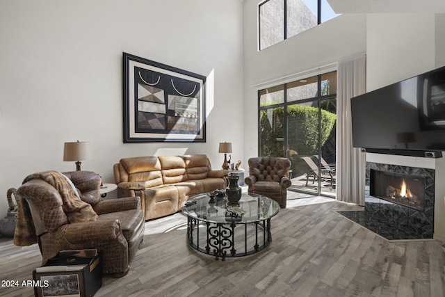 living room with a high end fireplace, hardwood / wood-style floors, and a high ceiling