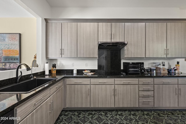 kitchen featuring black electric cooktop, dark stone counters, and sink