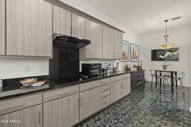 kitchen featuring pendant lighting, black electric cooktop, dark stone countertops, and light brown cabinets