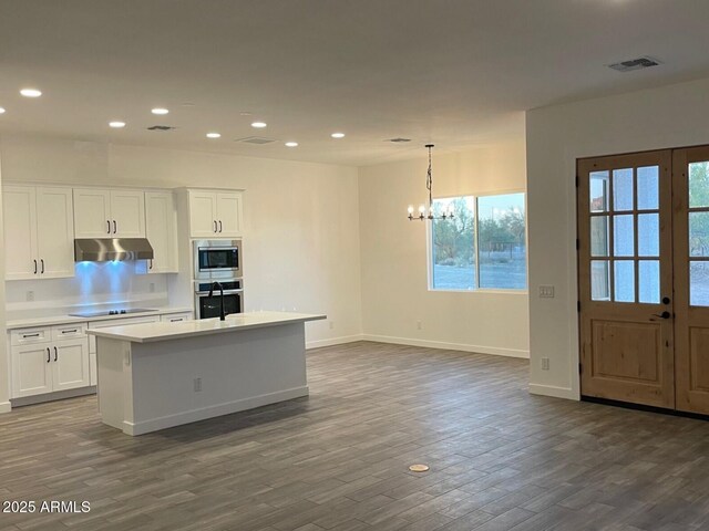 kitchen with visible vents, dark wood-style flooring, under cabinet range hood, appliances with stainless steel finishes, and white cabinetry