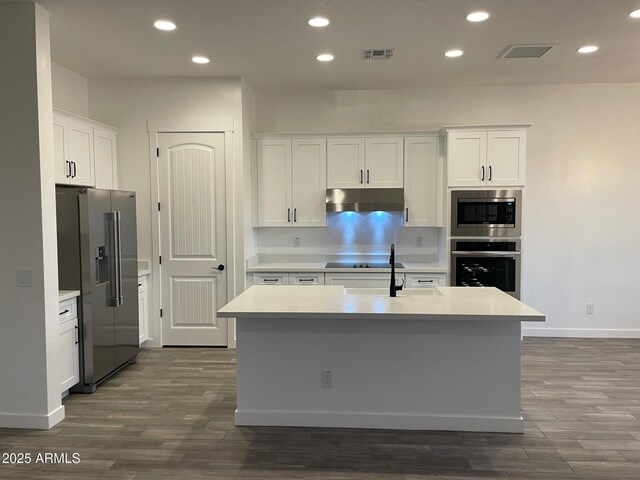 kitchen with visible vents, under cabinet range hood, white cabinetry, appliances with stainless steel finishes, and light countertops