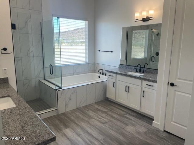 full bathroom featuring a shower stall, wood finished floors, vanity, and a bath