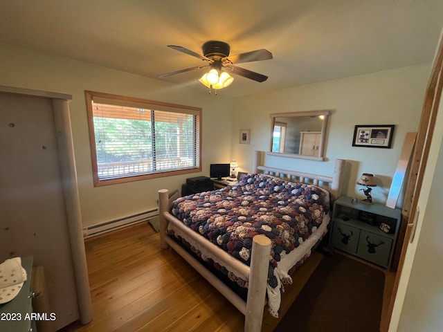 bedroom featuring ceiling fan, a baseboard heating unit, and hardwood / wood-style floors