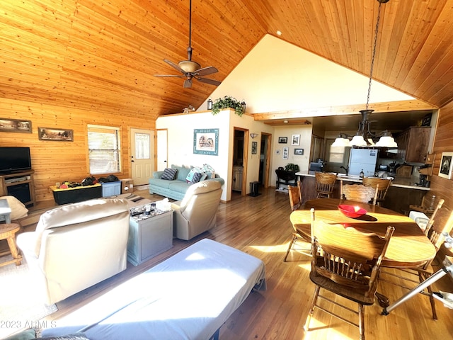 dining area featuring high vaulted ceiling, wood walls, ceiling fan with notable chandelier, wood ceiling, and hardwood / wood-style flooring