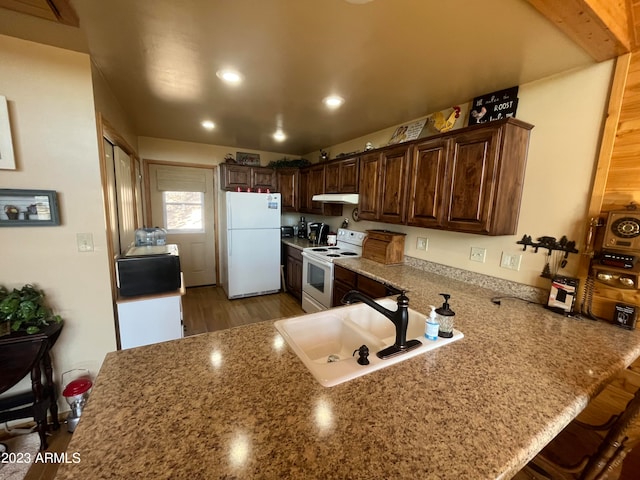 kitchen with white appliances, sink, a kitchen bar, dark hardwood / wood-style flooring, and kitchen peninsula