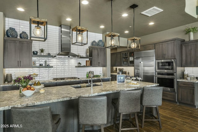 kitchen featuring backsplash, dark brown cabinets, sink, built in appliances, and range hood